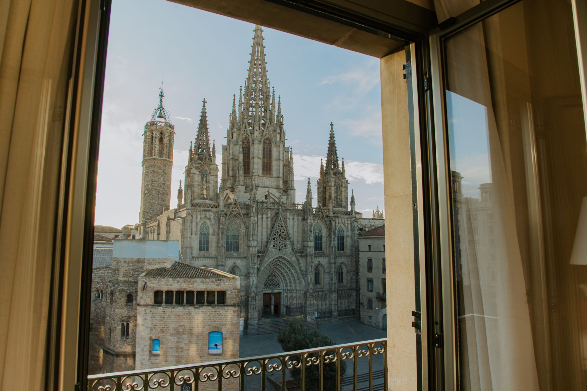 Fachada gótica de la Catedral de Barcelona y su plaza vistas a través de la ventana abierta y el balcón de la Premium Suite de Lamaro Hotel